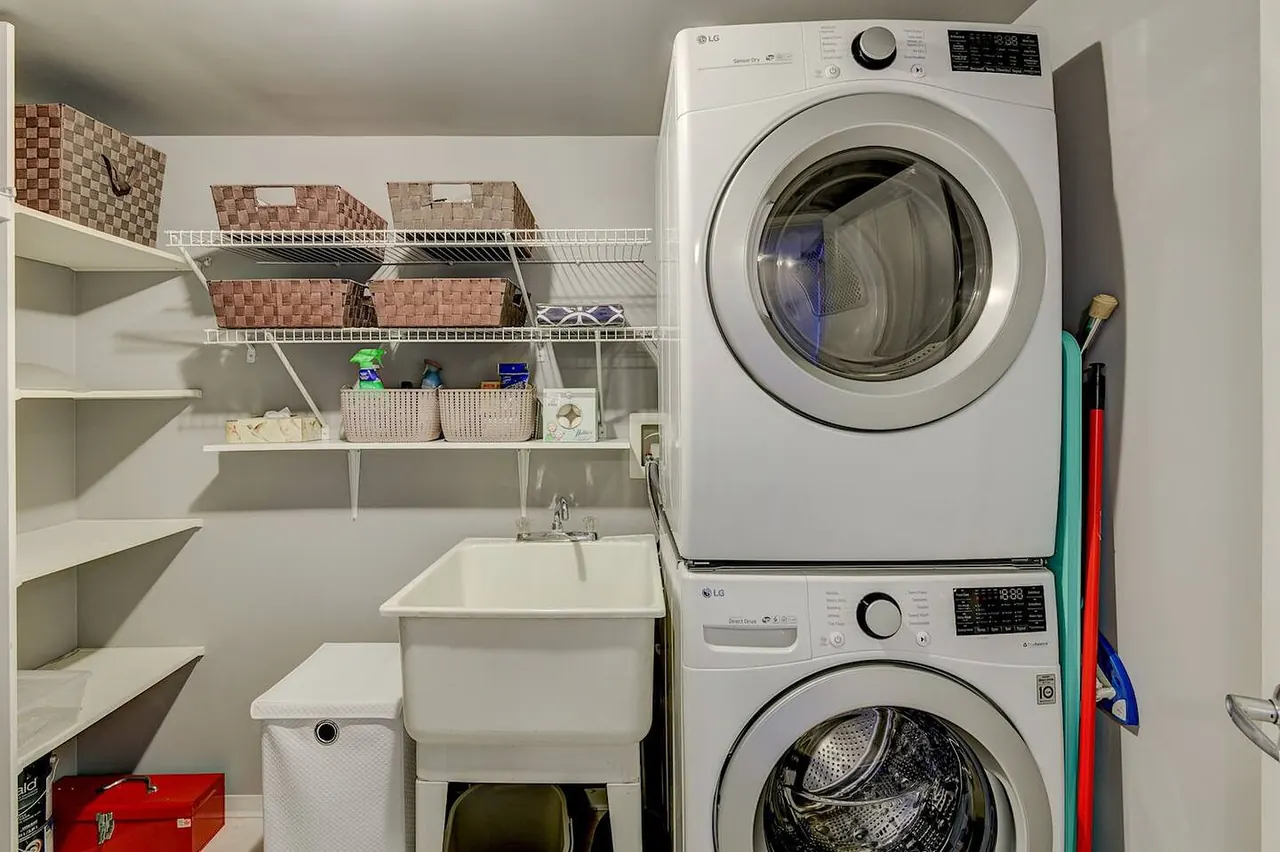 Laundry room with a stacked washer and dryer, laundry sink and shelving